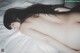 A naked woman laying on a bed with long black hair.