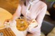 A woman pouring tea into a glass cup on a table.