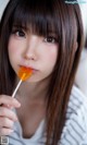 A young woman holding a lollipop in her mouth.