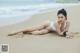 A woman in a white bikini laying on the beach.