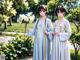 A couple of women standing next to each other in a park.