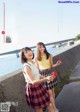 A couple of young women standing next to each other on a sidewalk.