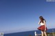 A woman standing on top of a hill next to the ocean.