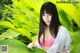 A woman in a pink bikini posing in front of a green plant.